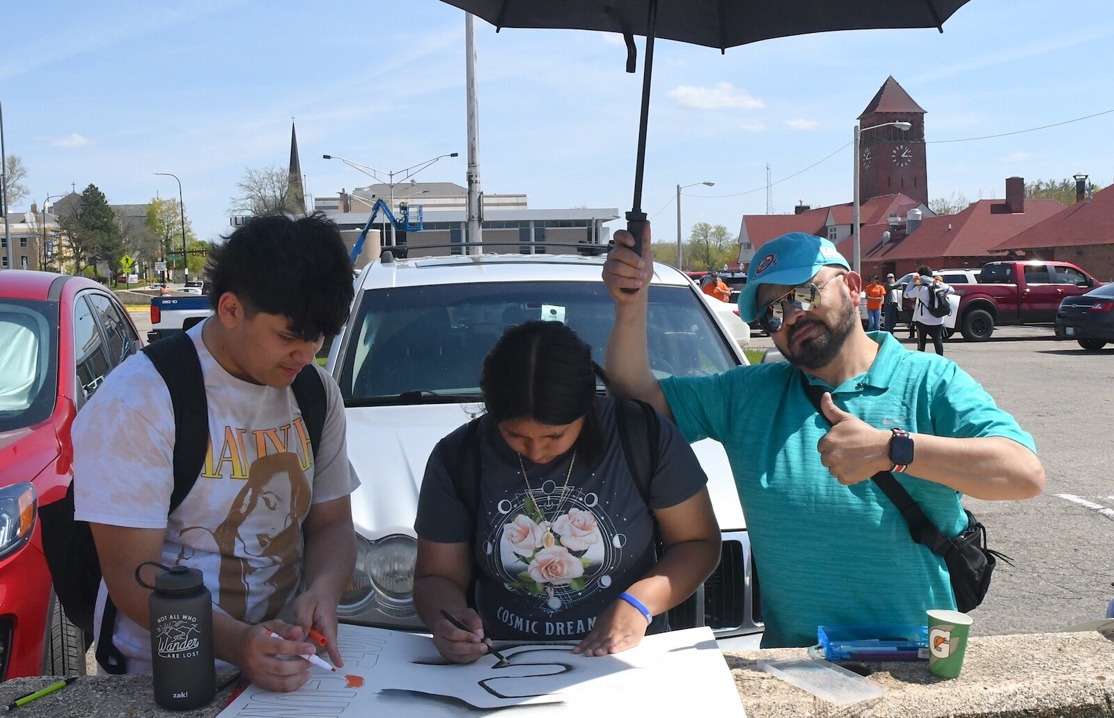 Preparing signs prior to an anti-gun violence march and rally in downtown Battle Creek are from left, Jon Contreras, Ariana Chavez, and holding the umbrella Albert Hernandes.