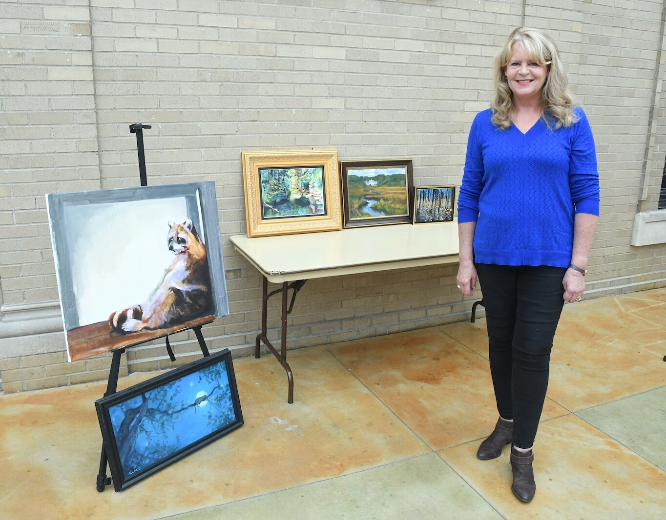 Tracy Goll is seen with some of her paintings.