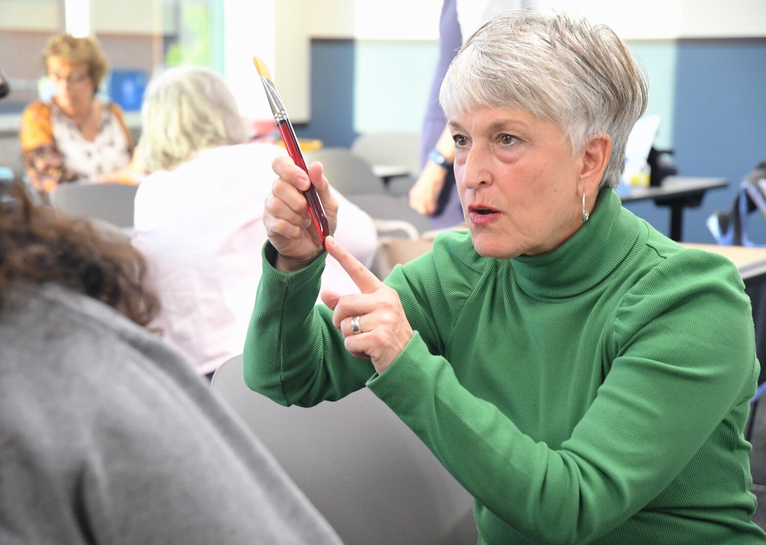 Liz Sweeney talks about brushes to one of her students during a Lifelong Learning waterclass class.