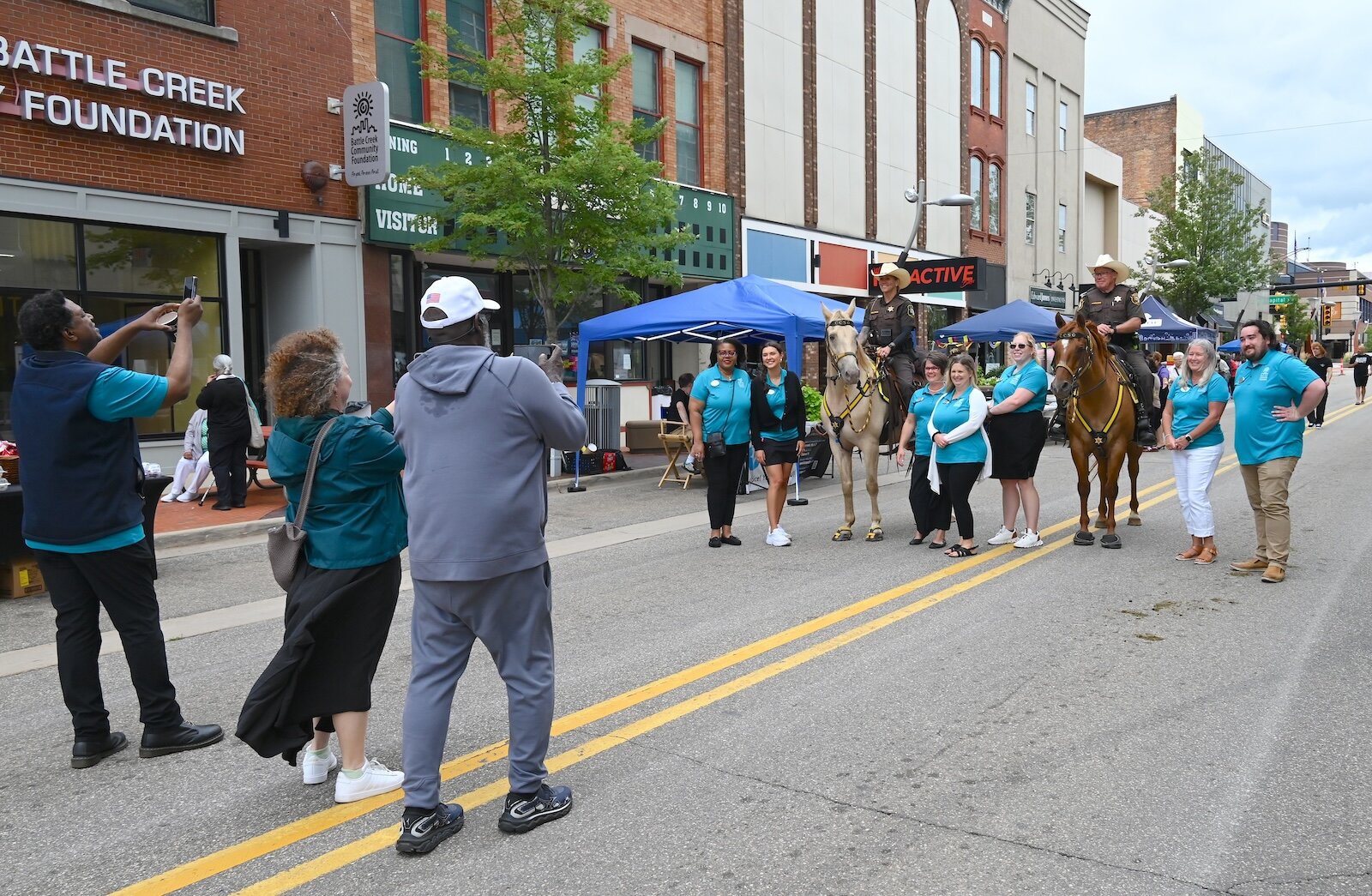 Staff of the Battle Creek Community Foundation pose with mounted members of the Calhoun County Sheriff’s Department.