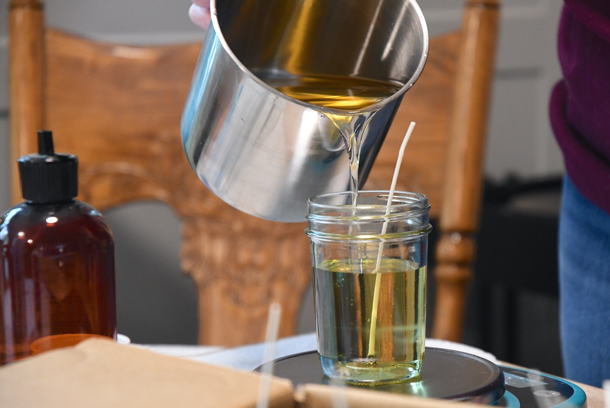 Kellee VanValkenburg draws hot soy wax into a container.