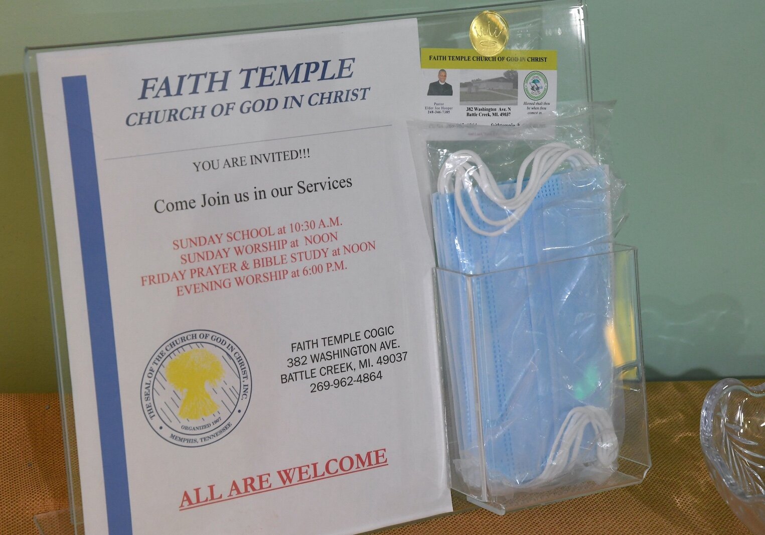 A welcome sign and face masks sit on a table near the entrace to Faith Temple Church of God in Christ.