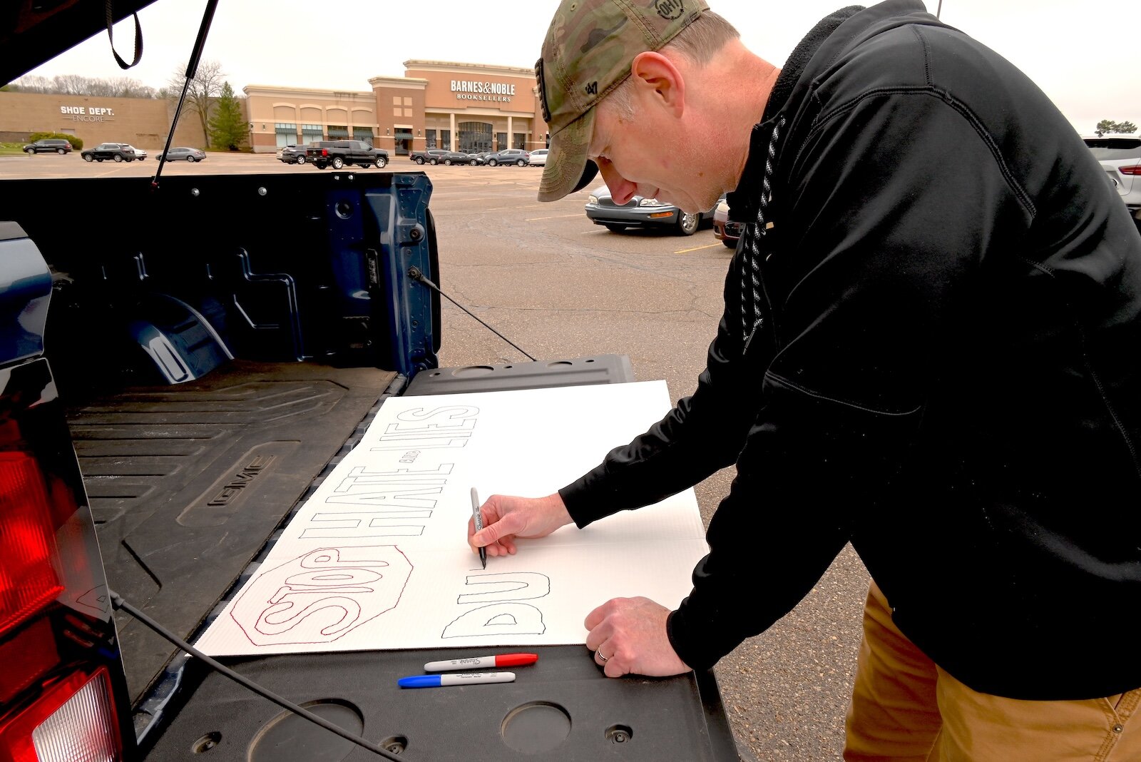Phil Wilkins prepares a sign for the April 5 Hands Off demonstration on Beckley Road in Battle Creek.