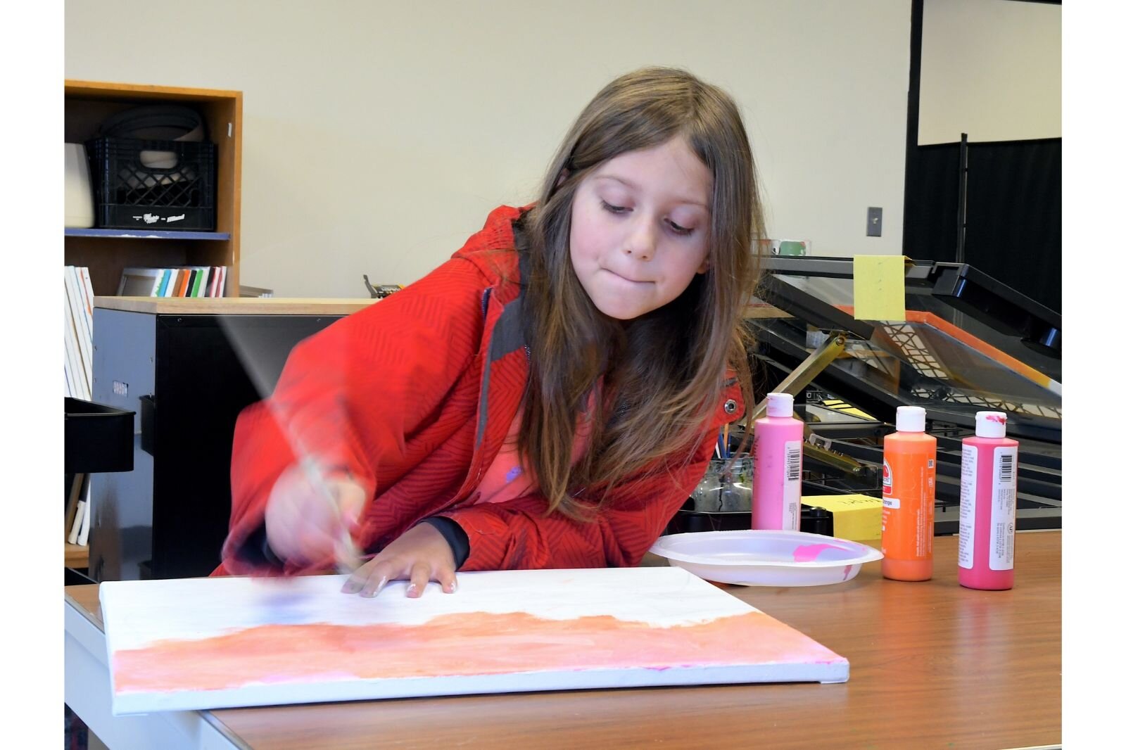 Cora Vance moves her paintbrush very fast while working on a painting.