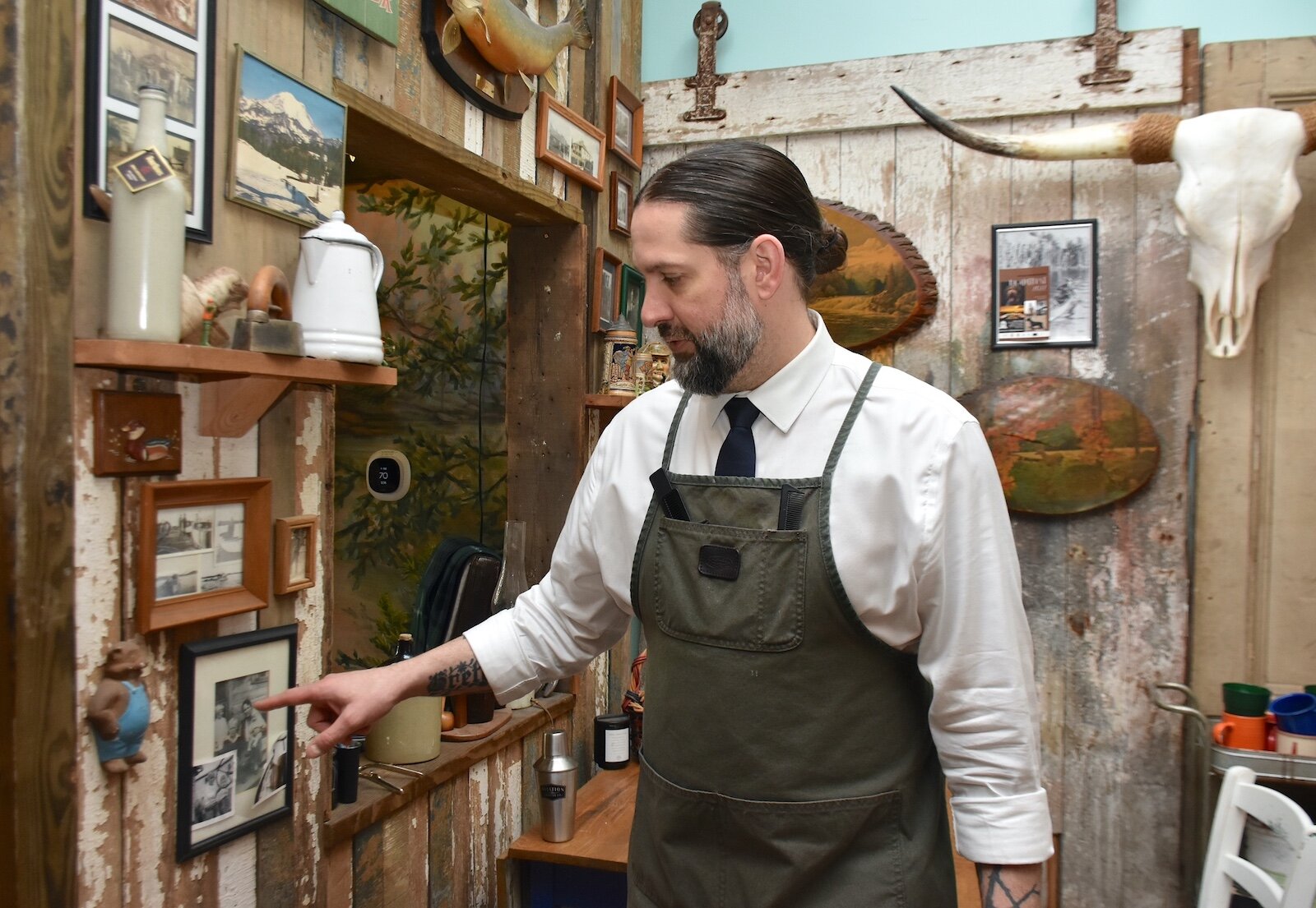 Noah Saber points out some family photos on the wall of his Camp barber shop in downtown Marshall.