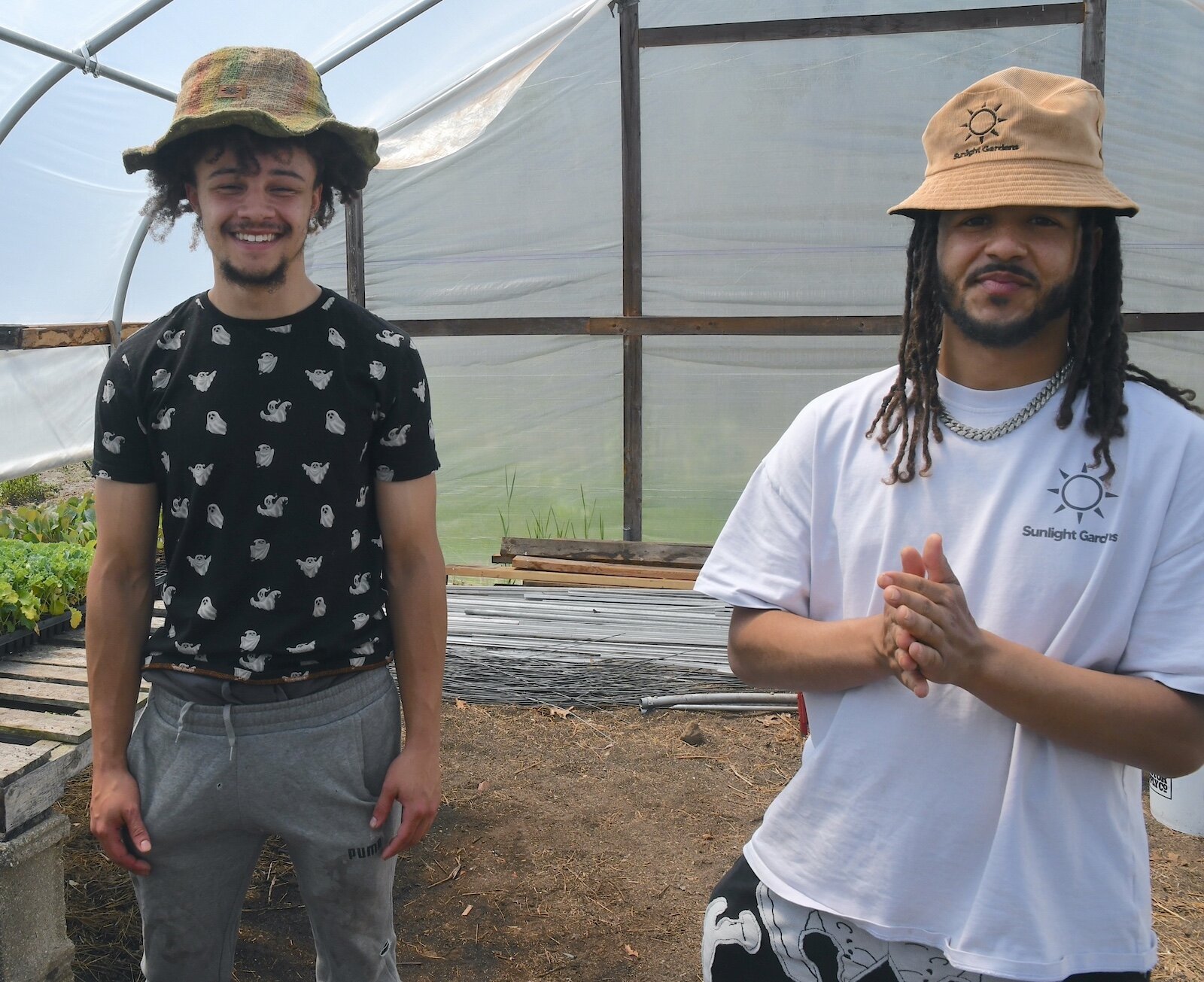 Devon Wilson, right, and Jerry Olds pose for photos inside a hoop house at Sunlight Gardens.