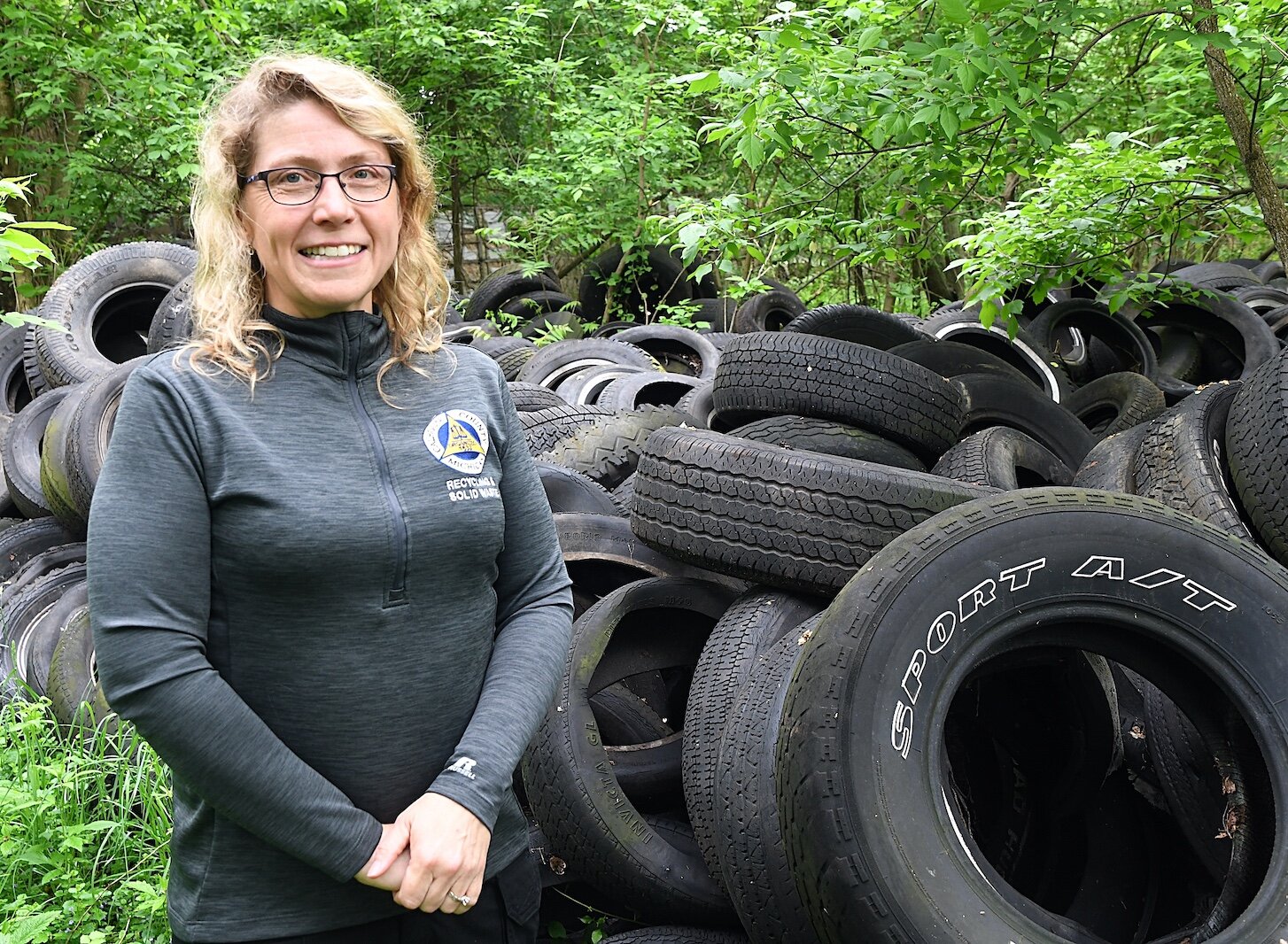 Sarah Kelly, Solid Waste and Recycling Coordinator for Calhoun County, stands in front abandoned old tires on property located on West Hamblin Avenue, just west of Butler Street, in Battle Creek.