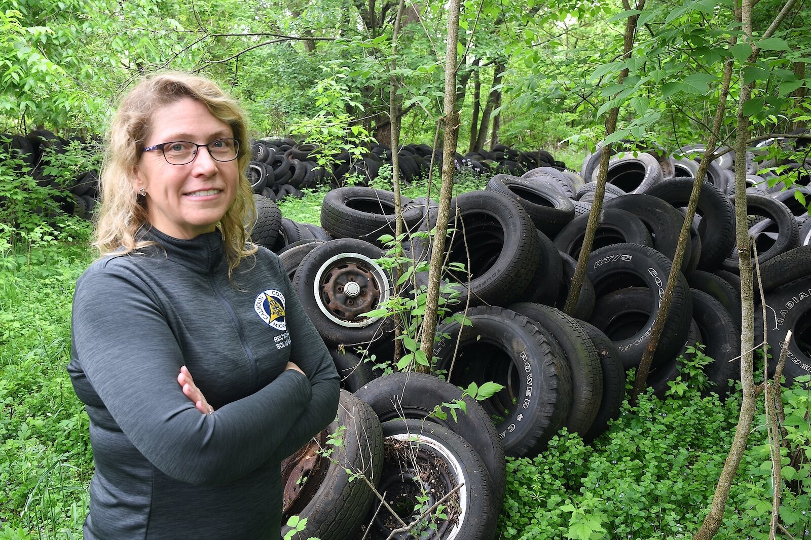 Sarah Kelly, Solid Waste and Recycling Coordinator for Calhoun County, stands in front abandoned old tires on property located on West Hamblin Avenue, just west of Butler Street, in Battle Creek.