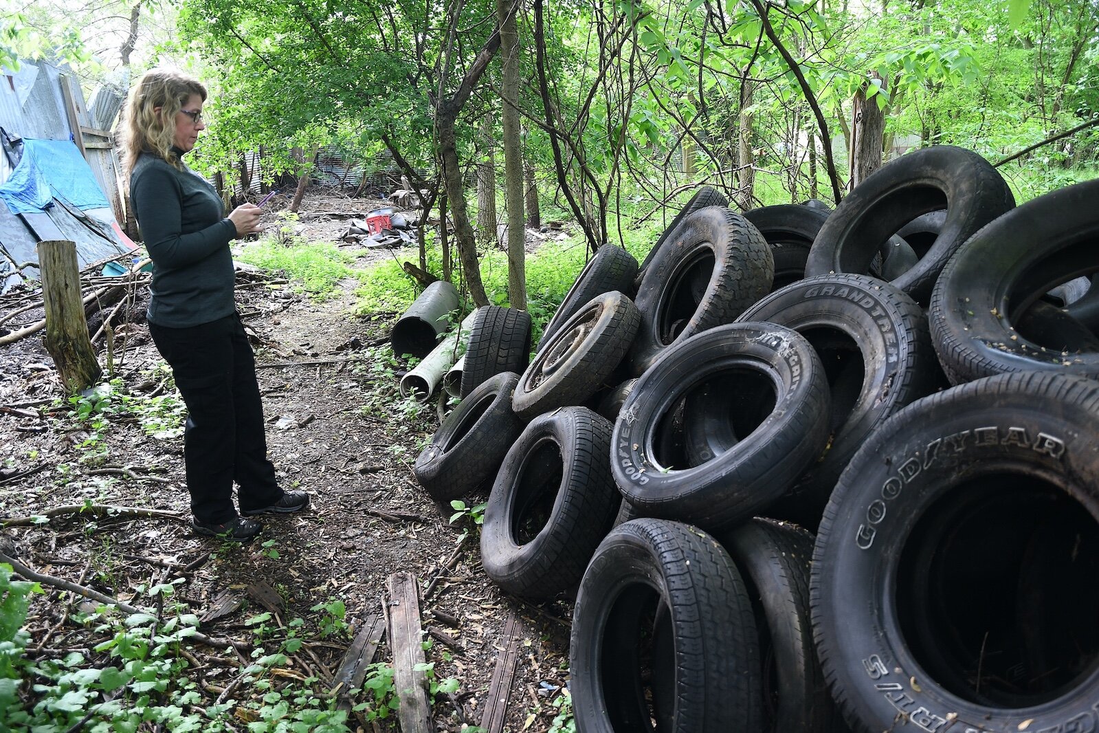 Sarah Kelly, Solid Waste and Recycling Coordinator for Calhoun County, views abandoned old tires on property located on West Hamblin Avenue, just west of Butler Street, in Battle Creek.