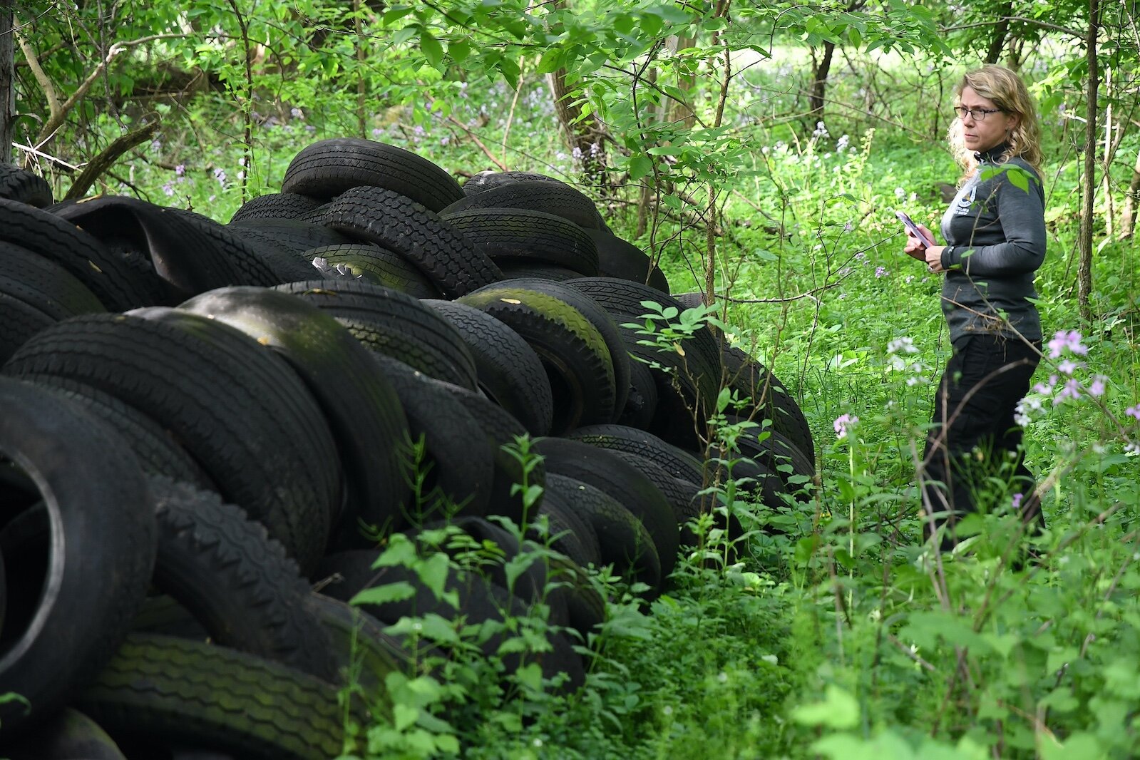 Sarah Kelly, Solid Waste and Recycling Coordinator for Calhoun County, views abandoned old tires on property located on West Hamblin Avenue, just west of Butler Street, in Battle Creek.