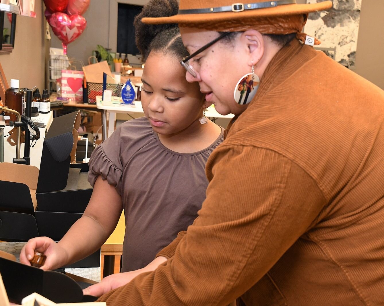Tiffany Blackman shows her daughter Kendall, 9, how to apply custom stamps to boxes in her store.