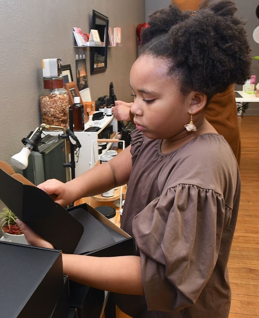 Kendall Blackman applies a custom stamp to a box in her mother’s store.