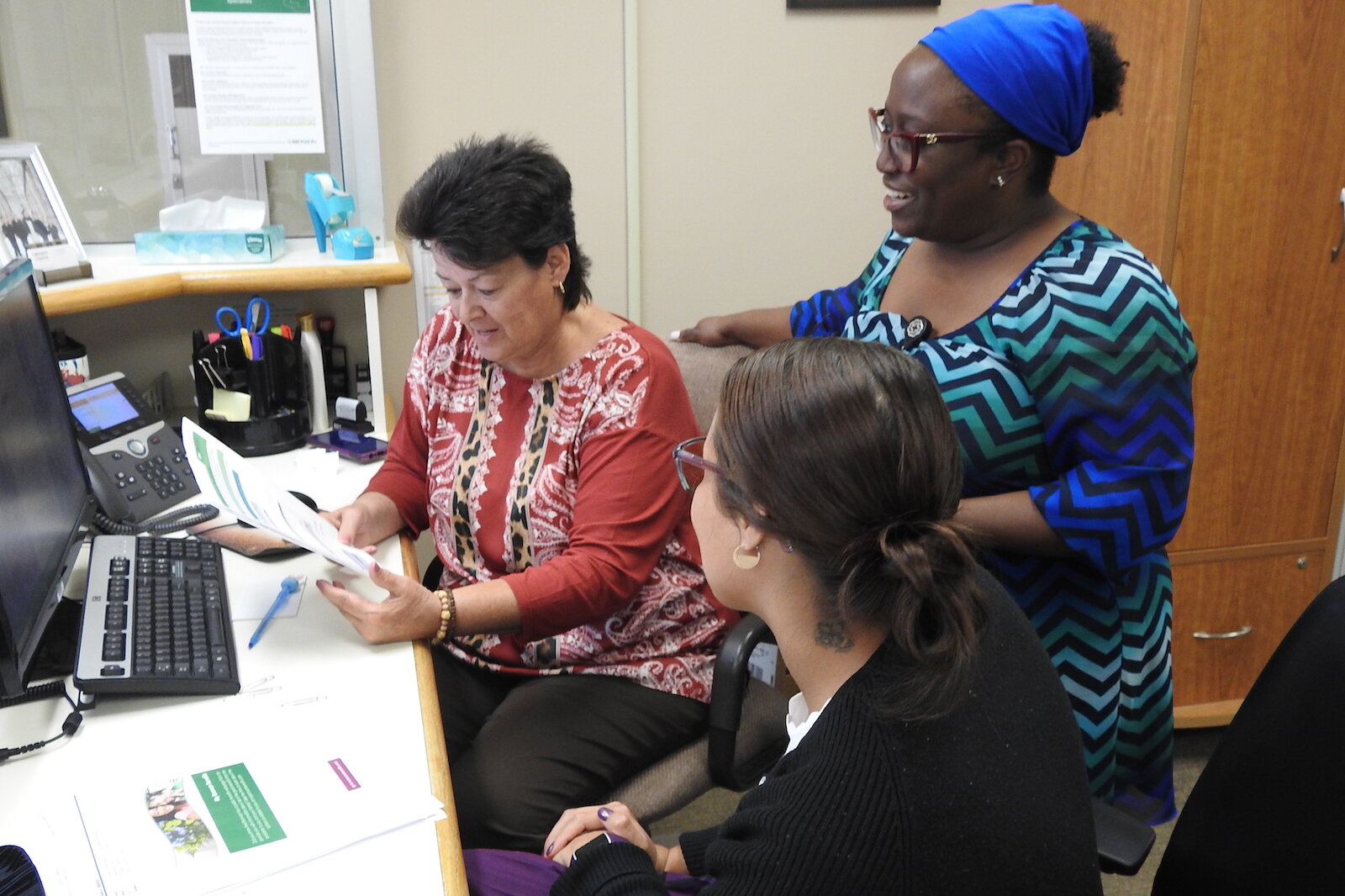 Elishae Johnson, directora de sistema de servicios de salud empresarial en Bronson Healthcare, consulta con la Especialista Administrativa Pam Milliron, a la izquierda, y la Especialista en Información Lexi King en Bronson Battle Creek Psiquiatría y 