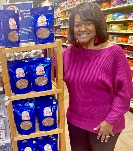 Papa’s Peanut Brittle is being sold at several local stores including Midtown Fresh, where company founder Doreen Gardner is shown standing next to a display.