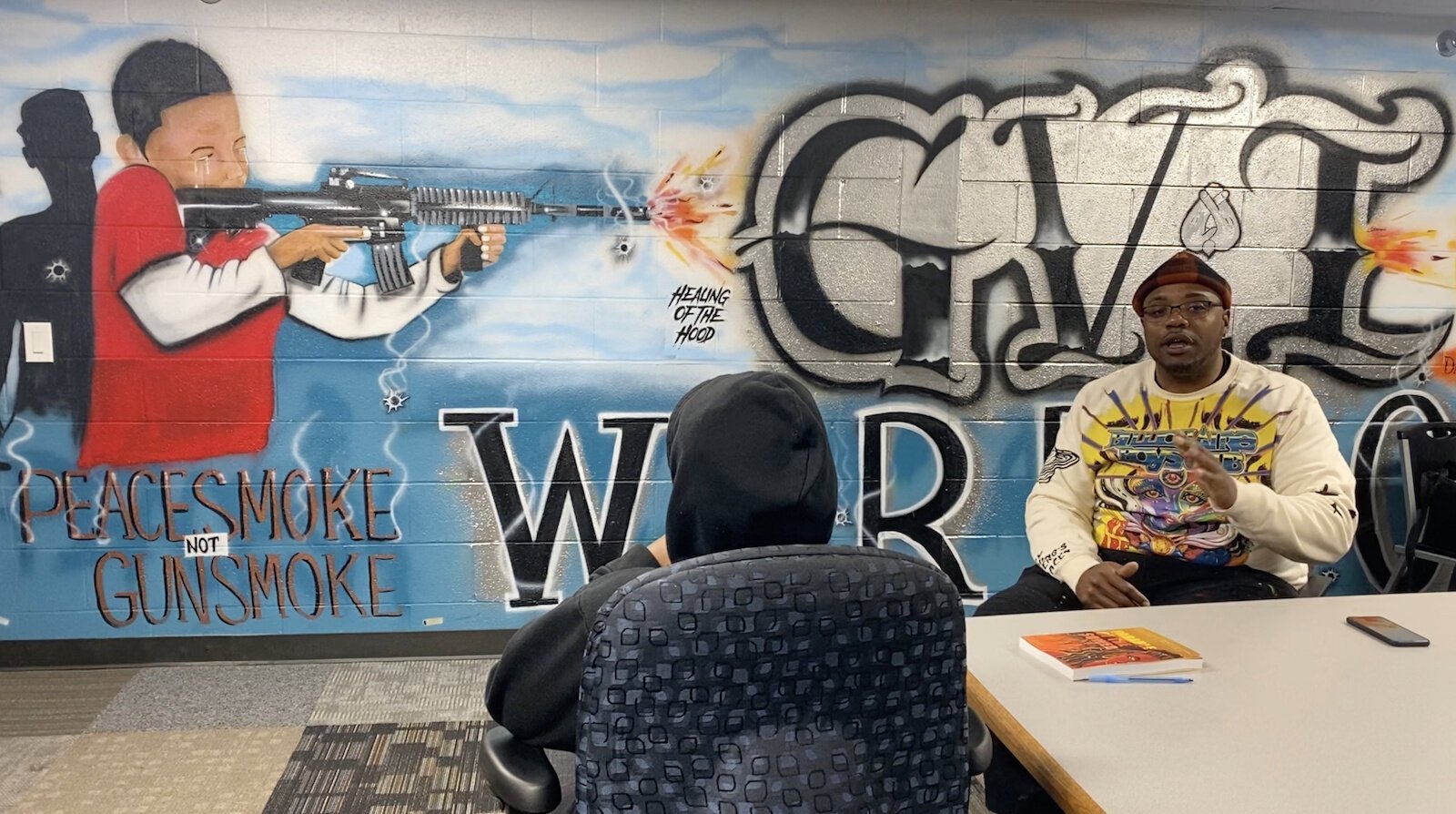 Yafinceio Harris speaks to a young man who was just released from the juvenile home, in Peace During War's "war room" in the Edison neighborhood. Ben Lando | NowKalamazoo