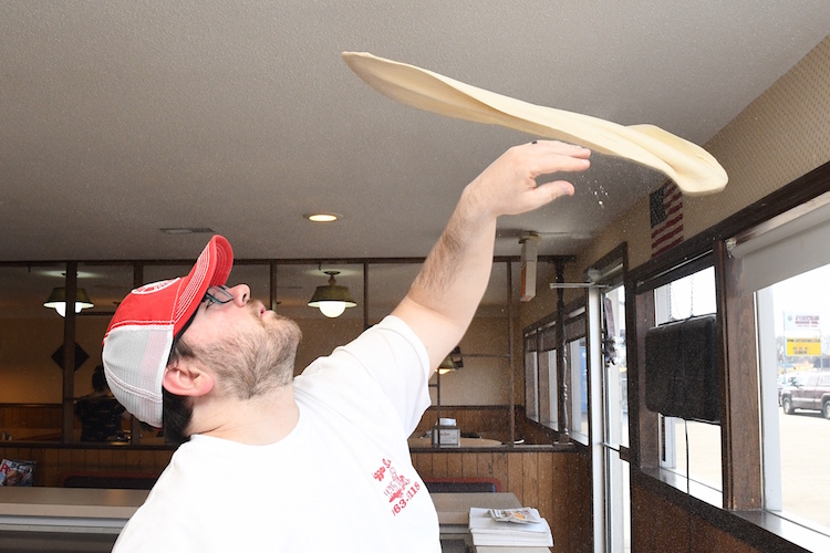 Jordan Wygant tosses pizza dough in the air at Pizza Sam’s.