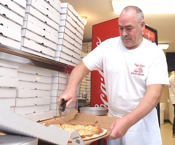 Tim Wygant slices a pizza at Pizza Sam’s.