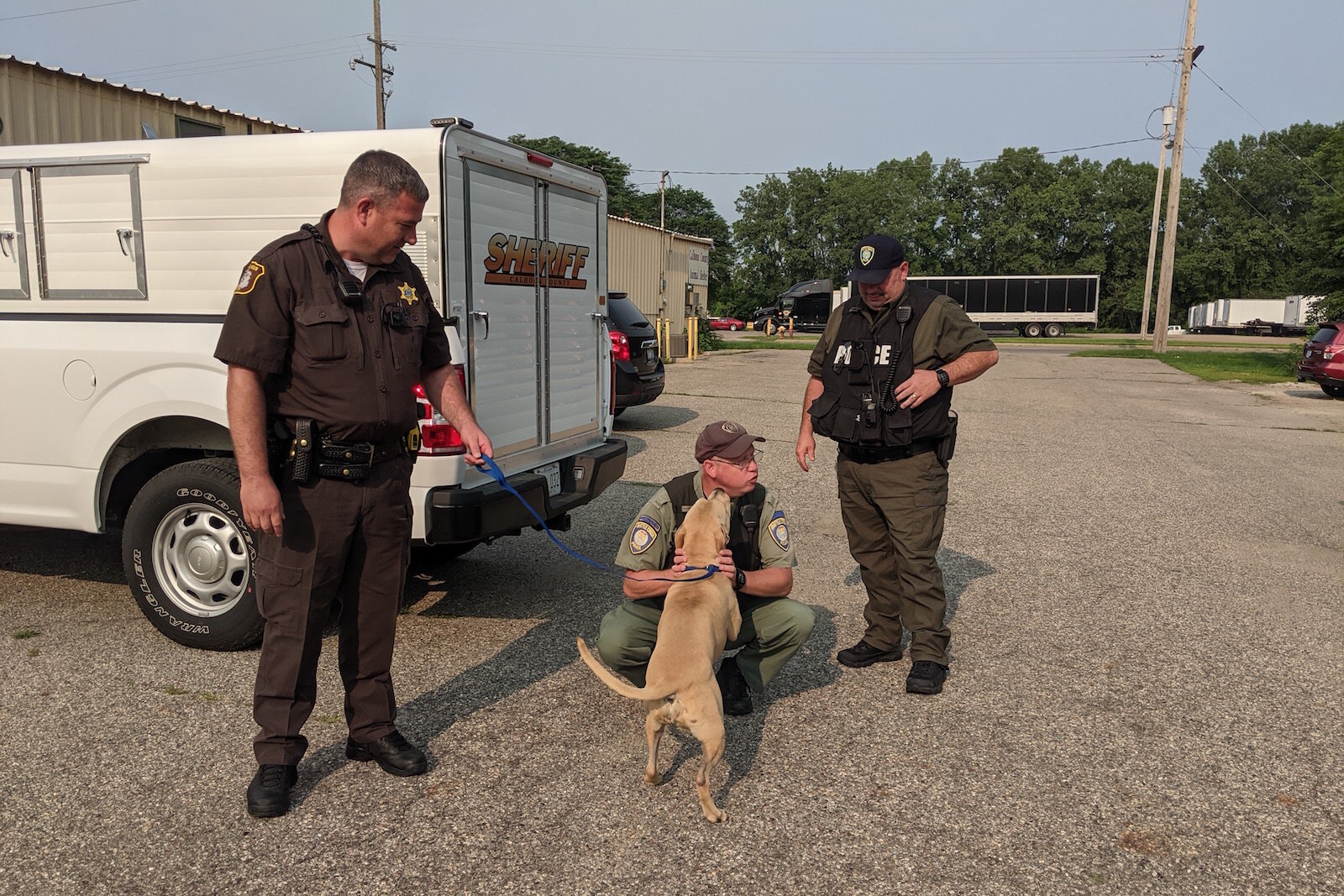 Deputy Michael Vanderbilt holds a dog who gets some attention from Officer Michael Ehart as his co-worker, Officer Pat Dellinger looks on.
