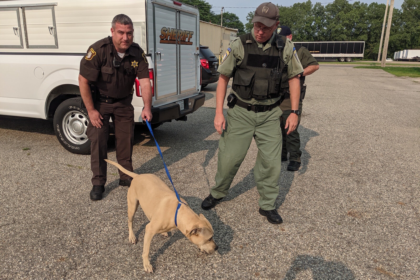 Deputy Michael Vanderbilt holds a dog that will be going back into the shelter as Officer Michael Ehart looks on.