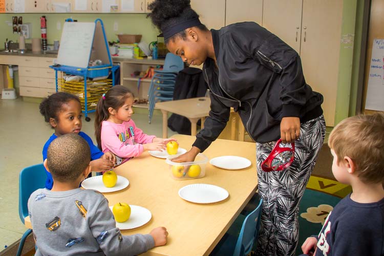 Nina Smith and children in the YWCA Children's Center eat an apple for a snack. Photo by Susan Andress