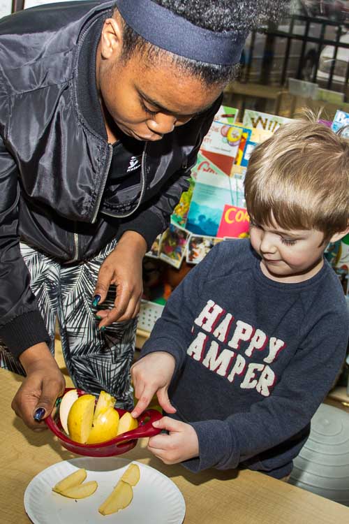 Nina Smith helps a youngster core an apple during snack time. Photo by Susan Andress