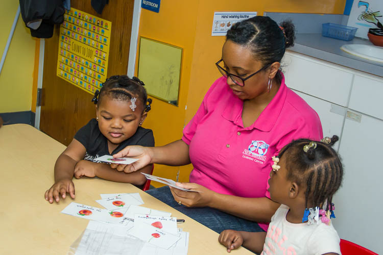 Preschoolers and Mrs. Karmin Armstrong-Andrews work together on learning at New Genesis.