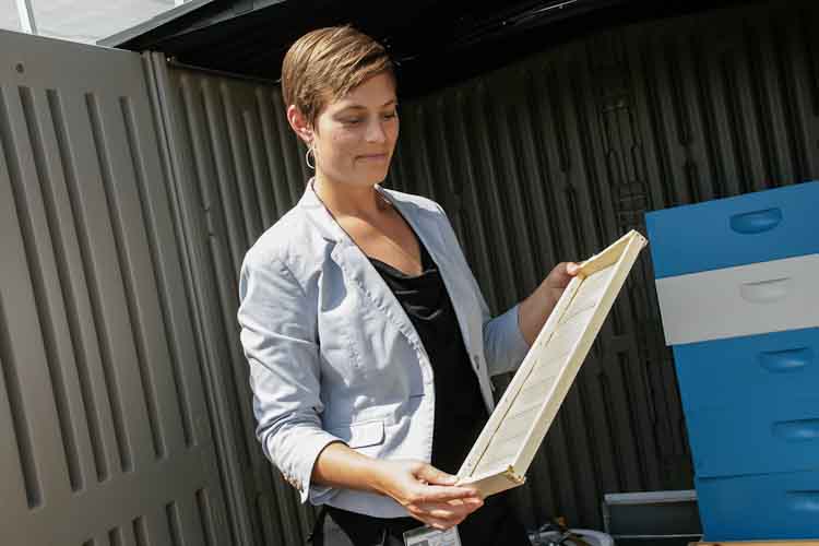 Rachel Bair works with a bee hive