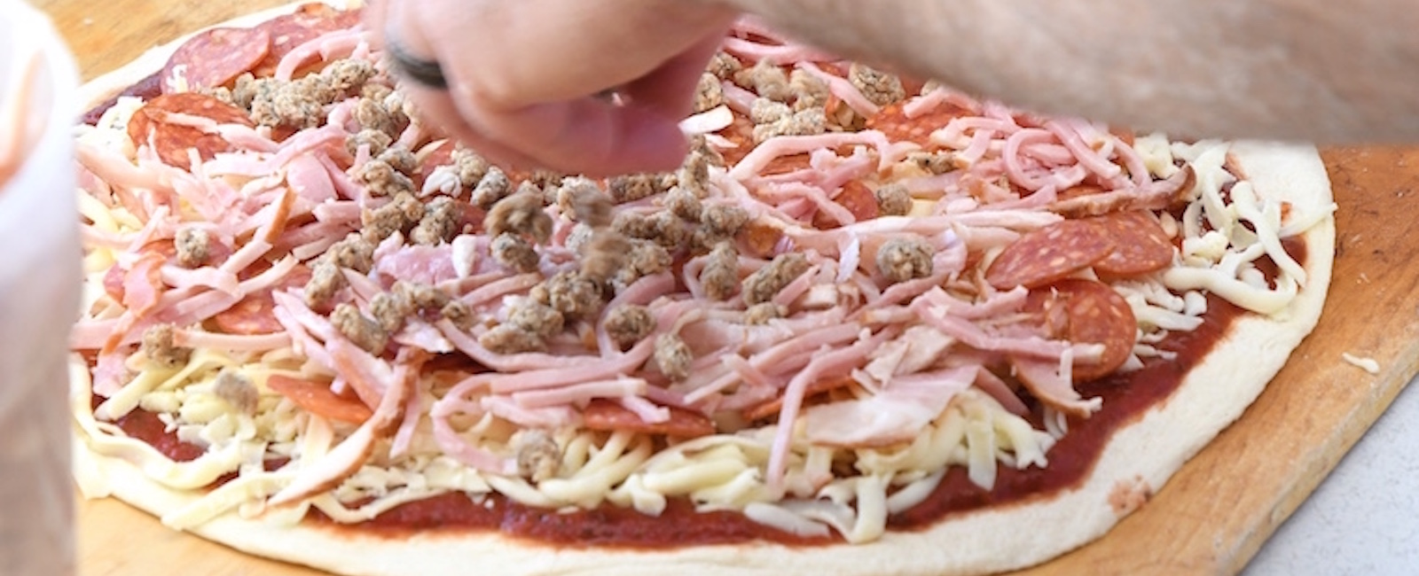 Jordan Wygant prepares a meat pizza at Pizza Sam’s.