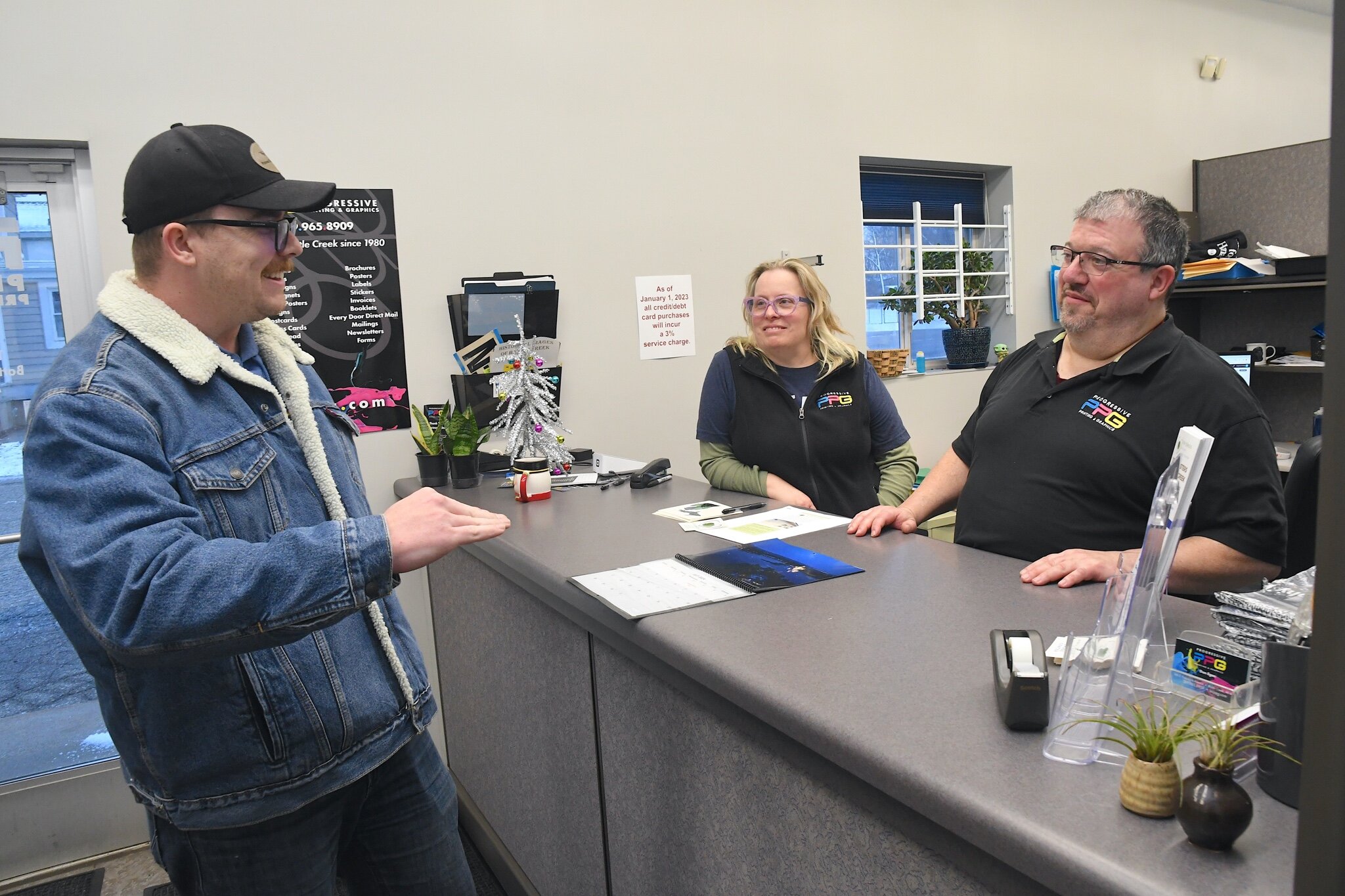 Patrick Bush of Patman Droneography, left, and Progressive Printing’s Karmel Addis and Dan Egan are seen in this photo. Progressive Printing are printing Patman Droneography artwork for a $50 donation to the SHARE Center.