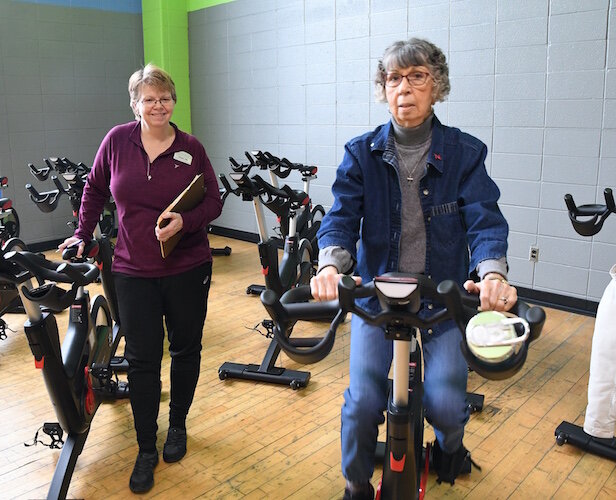 Susan VanderWeide, RN, Senior Health Partners clinical supervisor, watches Jeanette Gagnon participate in a spinning class for people with Parkinson’s Disease at the YMCA.