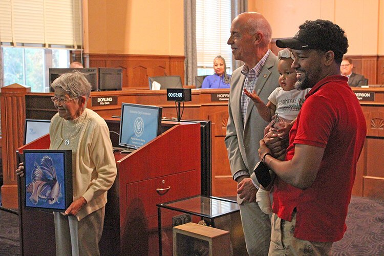 Tsugi Ogane holds a painting of a koi by Kalamazoo artist Gay Walker.given to her  by the City of Kalamazoo. At center is Kalamazoo Mayor David Anderson and at right is former city commissioner Eric Cunningham who has visited Namuzu.