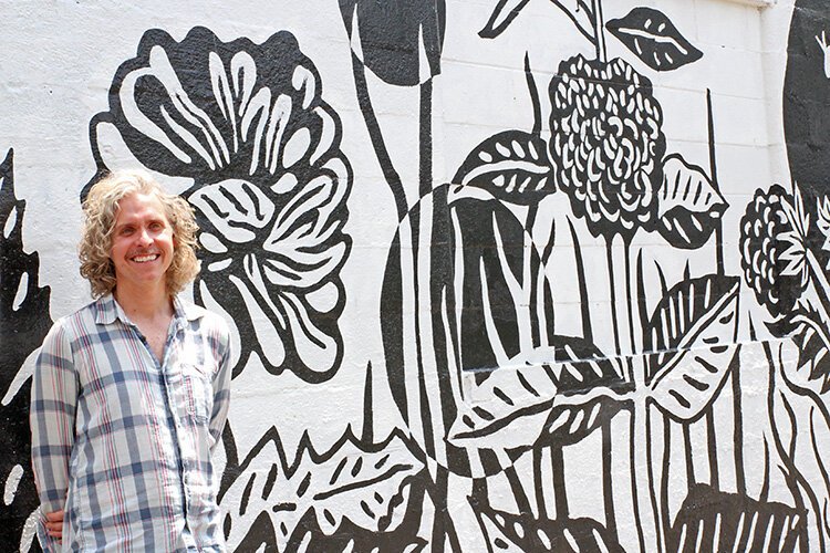 Stephen Dupuie, executive director of the Edison Neighborhood Association stands by the mural on the ENA office building.