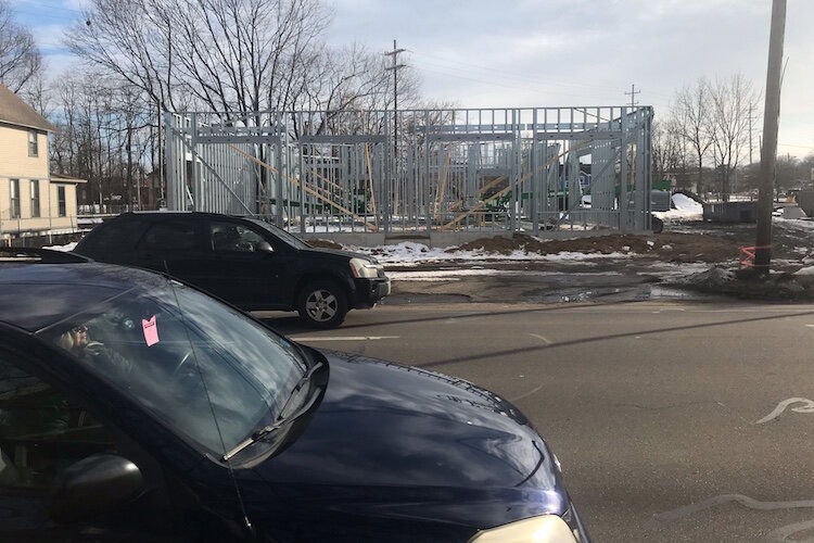 Cars stream along the 600 block of West Kalamazoo Avenue in front of the steel framing for one of the two Westgate Commons buildings under construction there. Each will be a three-story structure with masonry on the exterior of its ground level and a