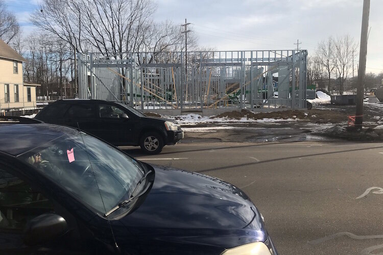 Cars stream along the 600 block of West Kalamazoo Avenue in front of the steel framing for one of the two Westgate Commons buildings under construction there. Each will be a three-story structure with masonry on the exterior of its ground level and a