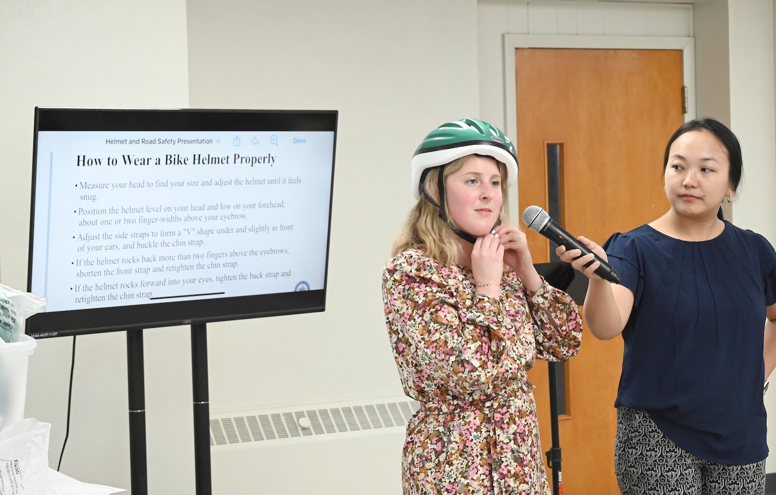 Hannah Sloss, left, and Christina Sawnset, at the Calhoun County Health Department, show the proper way to wear a bicycle helmet.