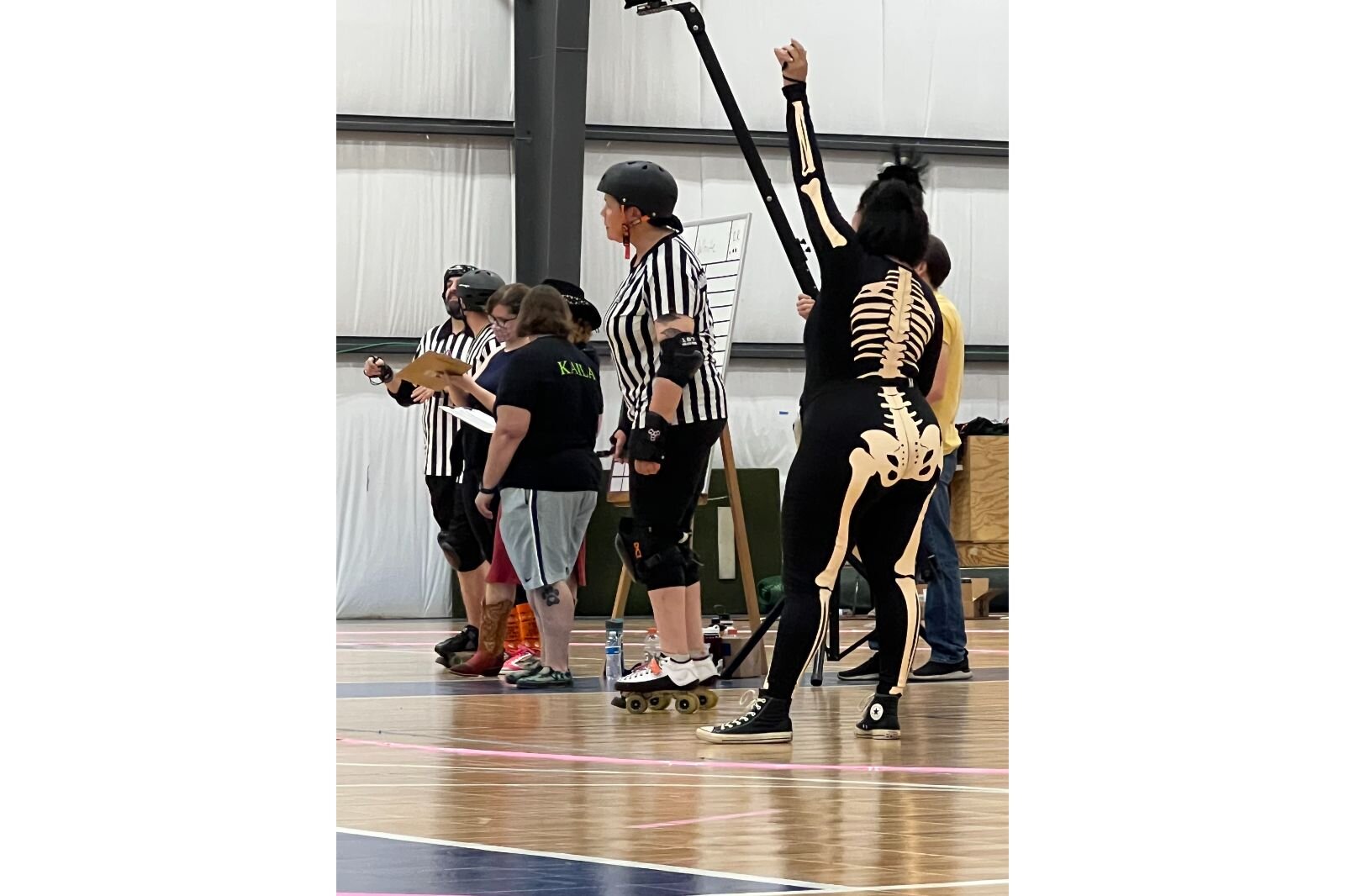  In the middle of the rink, several referees stand consulting with one another, some even in costume