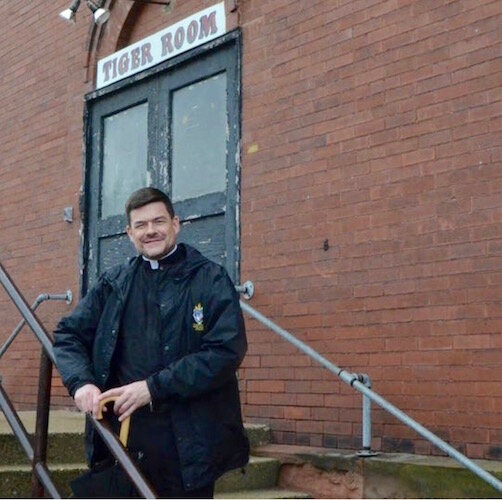 Father John Fleckenstein on the steps at the Van Buren Street entrance to the Tiger Room. A $4 million renovation of the building will convert it into an Accelerator for foodnd beverage product businesses.