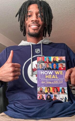 Trevon Henry, a contributing author, holds his first copy of How We Heal.