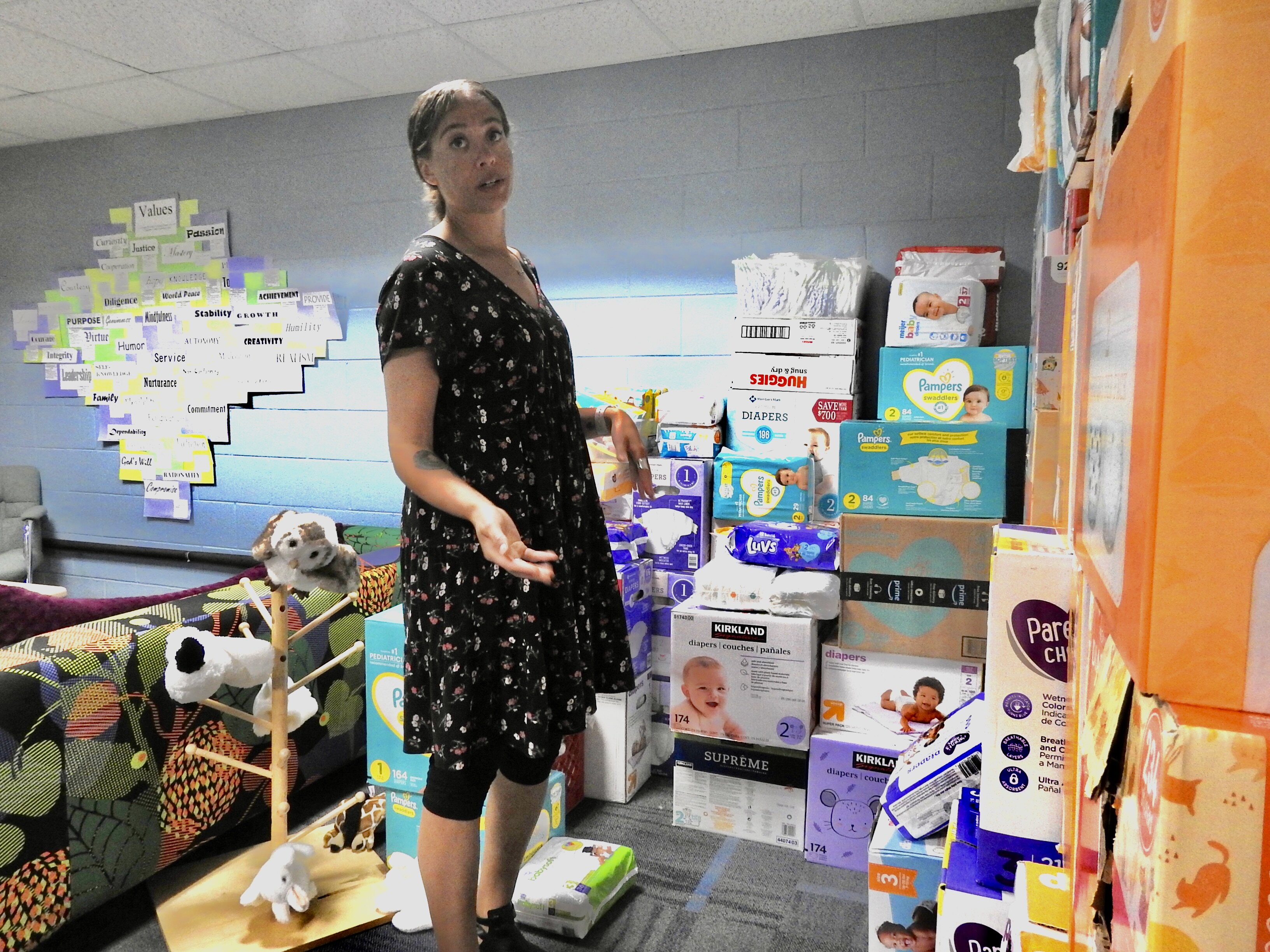 Victoria Orbe, children’s services director for Community Healing Centers in Kalamazoo, stands near diapers collected for struggling parents. Student loan debt assistance could equip more mental health workers to help struggling children, Orbe says.
