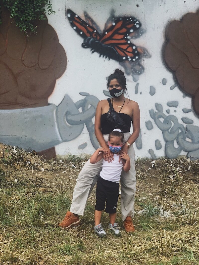Victoria Fox-Ramon stands with her daughter in front of a mural in Battle Creek. She ubmitted a poem that highlights her relationships with the people who raised her.
