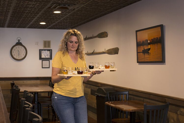 Owner, host, and winemaker of TwoRivers Winery, Julie Swantek, brings out a flight of wine for customers.