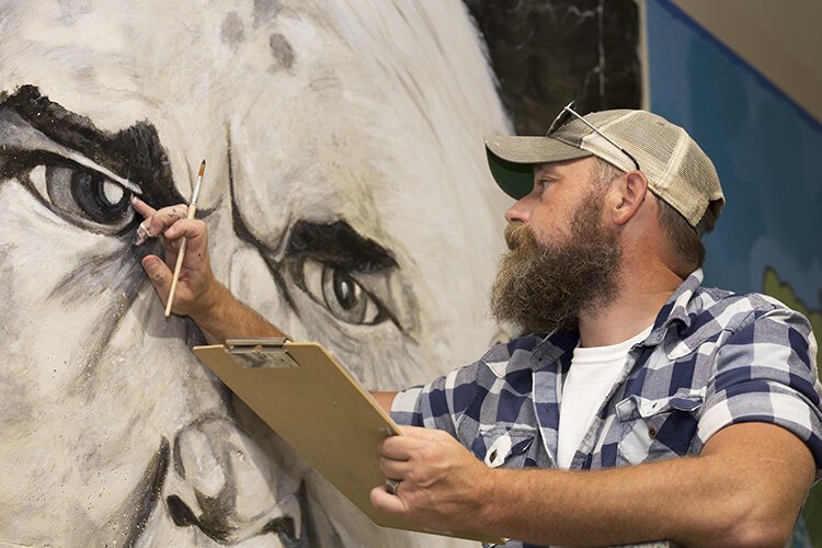 Artist Jeremy Thornton works on his mural depicting Thomas Edison.