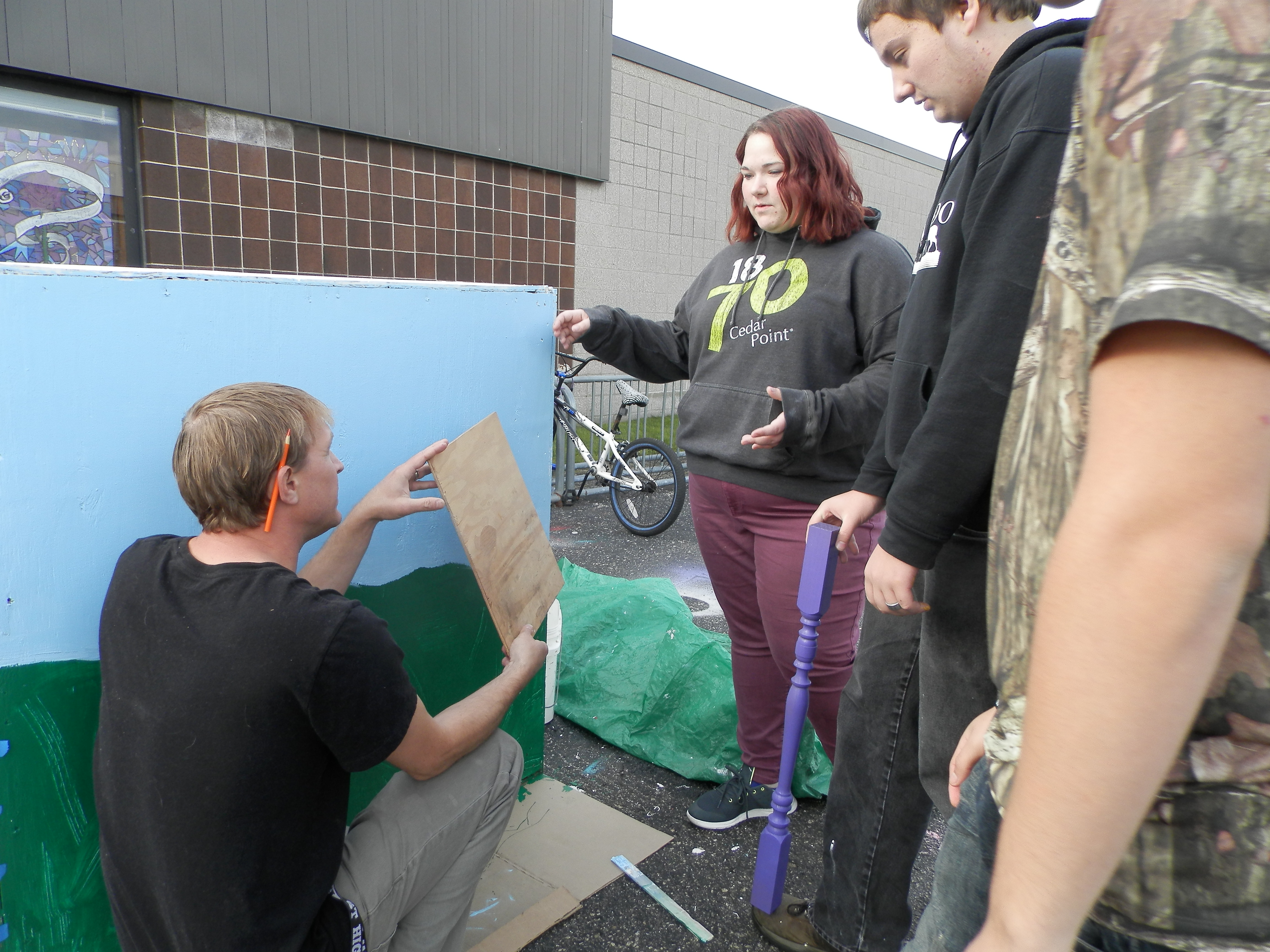 Art teacher Jason Stier gives some instruction on how to create a drop-down shelf on a side of the box.