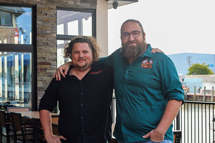 Co-owner Robert Harrison (left) poses for a photo with General Manager Jeff Bennett on the patio at Bootleggers Axe Co.