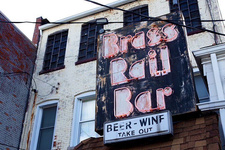 An aging neon sign hangs over the rear entrance of the Brass Rail Bar.