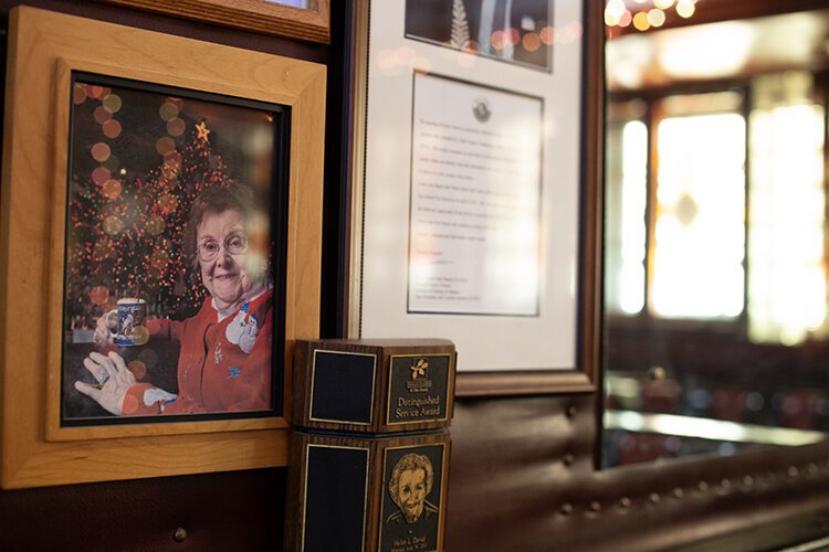 A photo of the Brass Rail Bar's original owner, Helen David, holding the bar's iconic Tom and Jerry hangs on the wall.