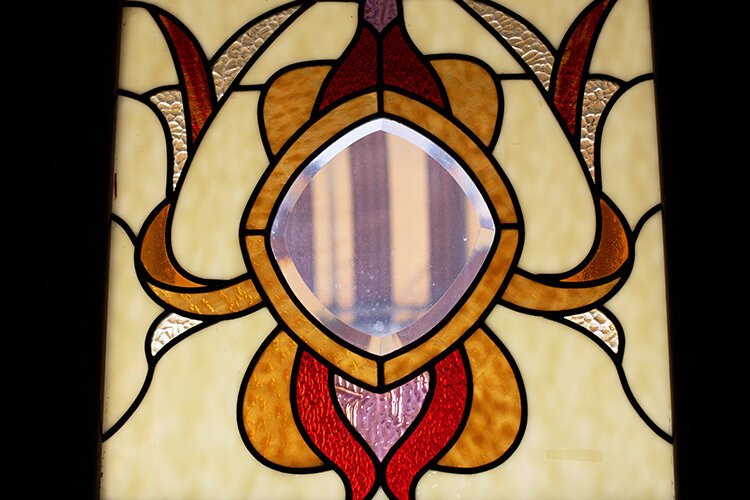 Sunlight comes through a pane of stained glass on the front door of the Brass Rail Bar.