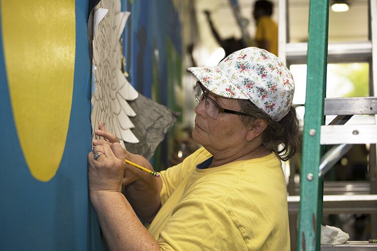 Artist Diane Bissland works on her vibrantly-colored, flower-themed mural.