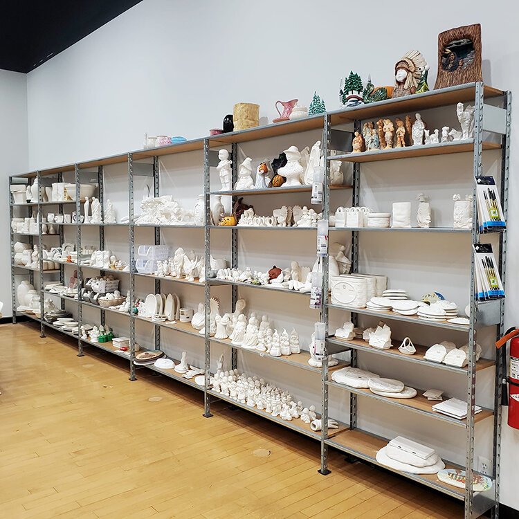 A shelf offering a variety of ceramics pieces is displayed at A Little Hobby Ceramics Studio.