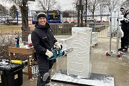 Katlin Pfroffer poses for a photo while working on her ice sculpture during St. Clair's Icy Bazaar.